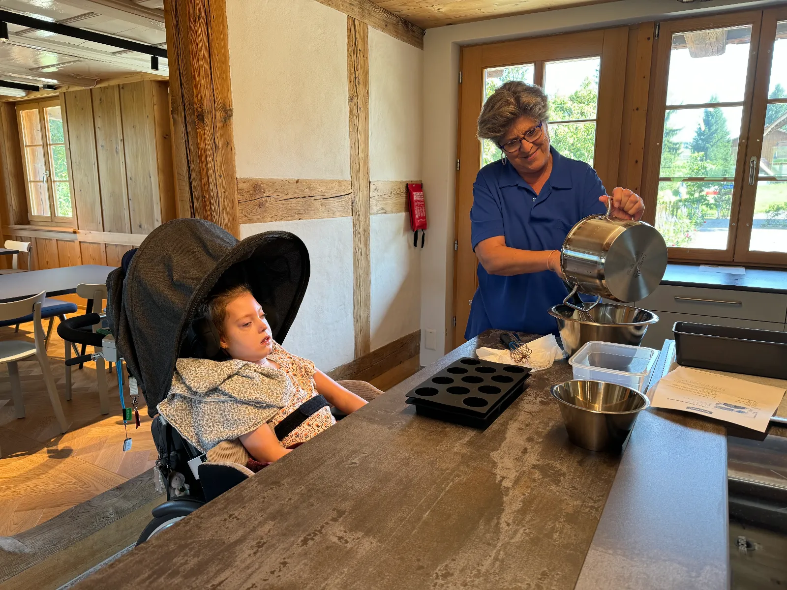 Person backt in der Küche, Kind beobachtet an der Theke