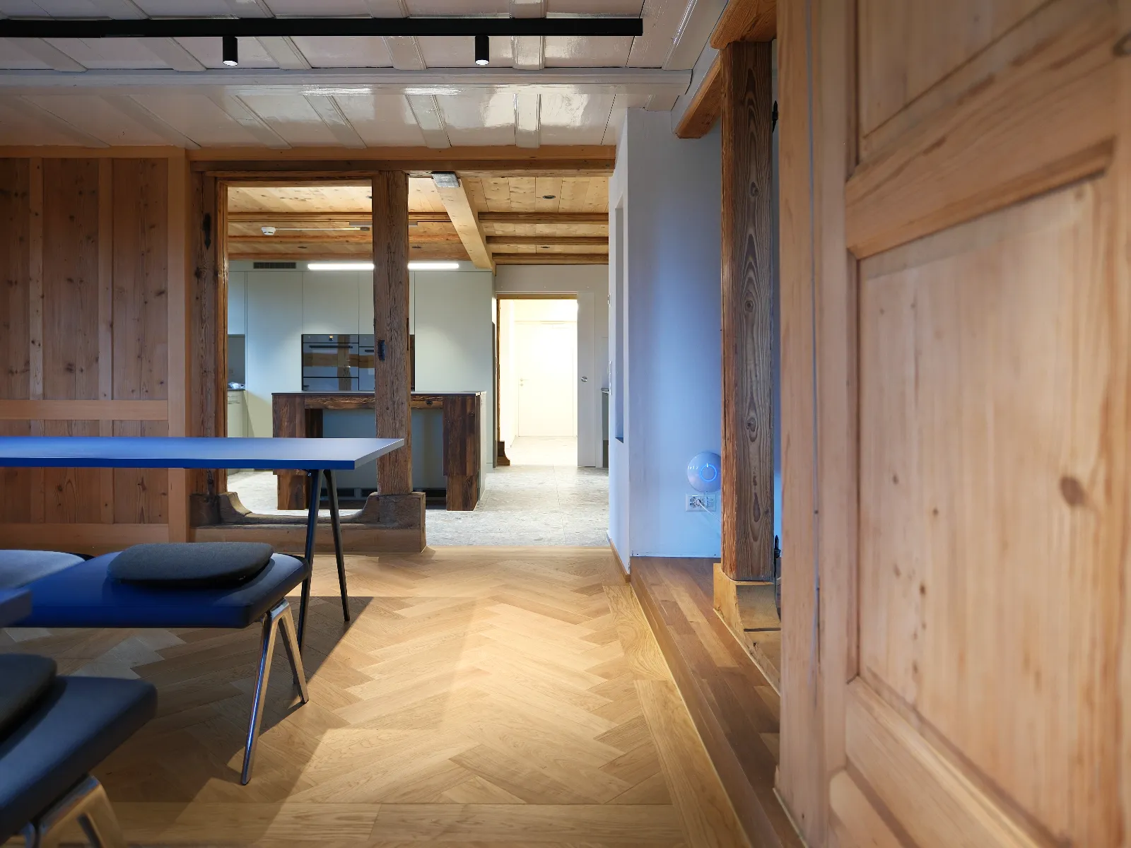 Blaue Esstische im Vordergrund mit Küche im Hintergrund