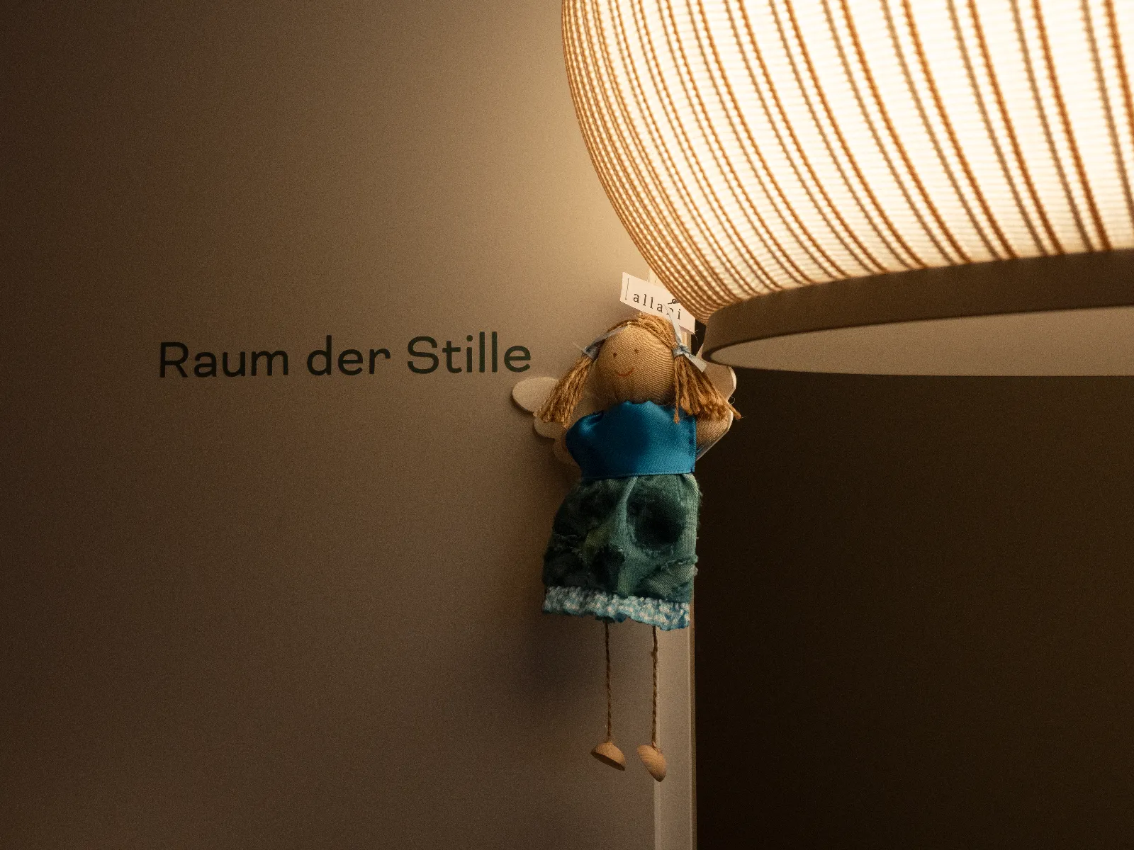 Handgenähter Engel unter einer leuchtenden Dekolampe