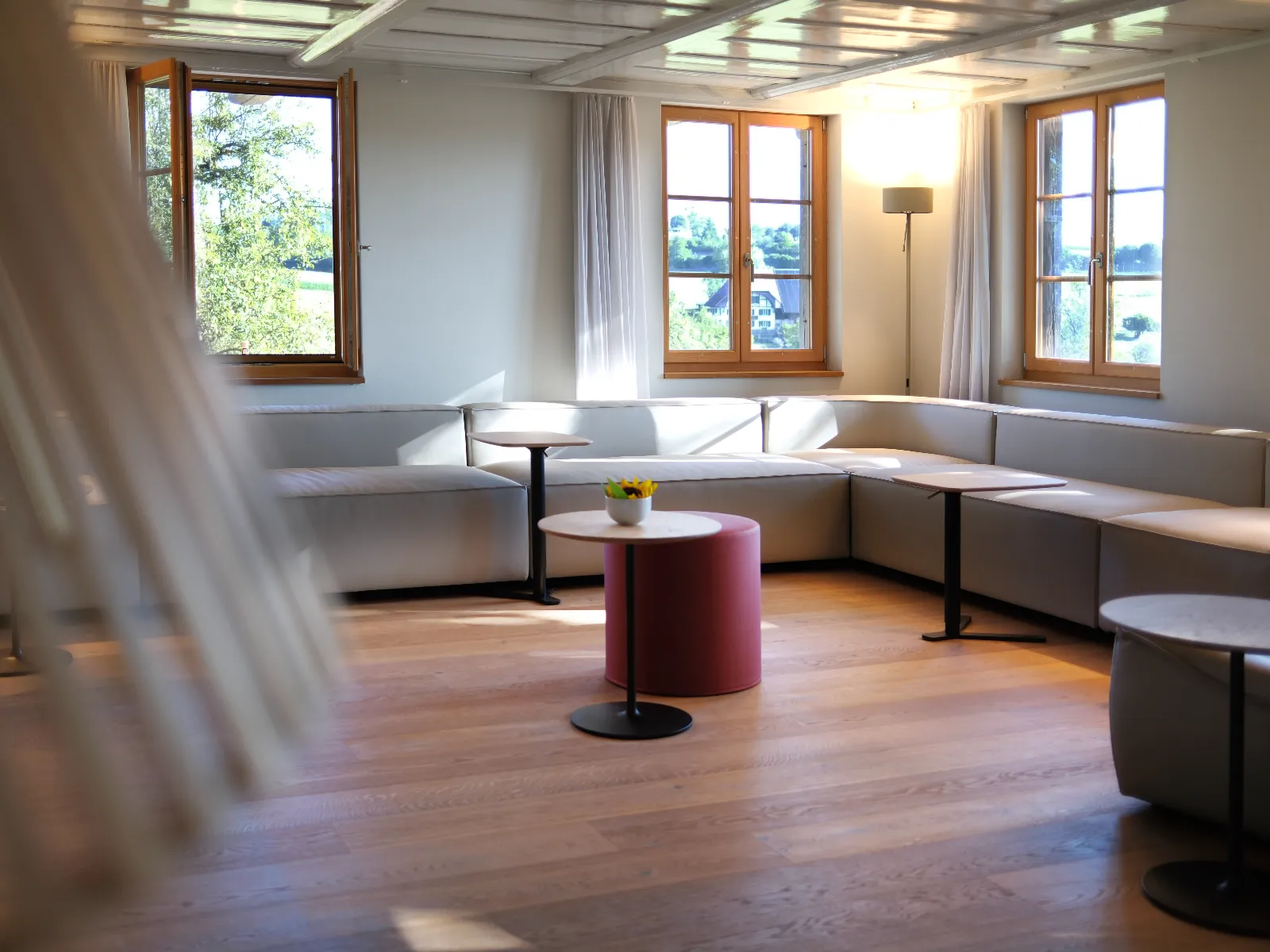 Weisse Couch im Wohnzimmer unter mehreren Fenstern