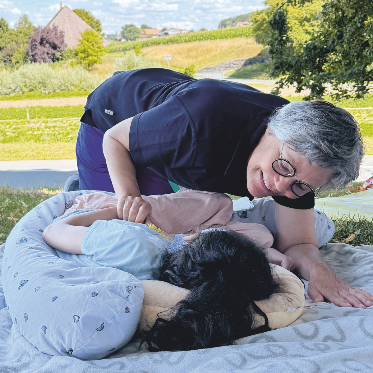 Pflegeperson betreut ein Kind auf einer Wiese im Freien