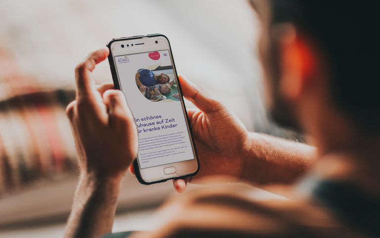 Smartphone in der Hand einer Person mit der allani Website auf dem Bildschirm
