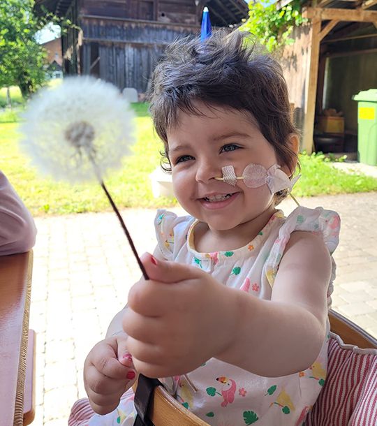 Kind mit Pusteblume in der Hand
