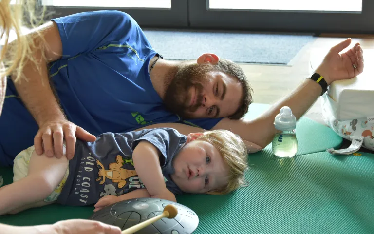 Vater und Sohn bei einer Musiktherapie, liegend auf dem Boden