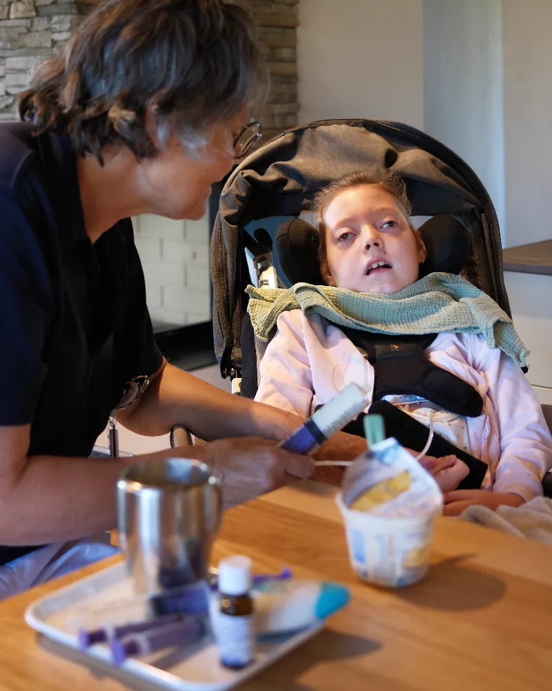 Pflegeperson betreut ein Kind im Rollstuhl